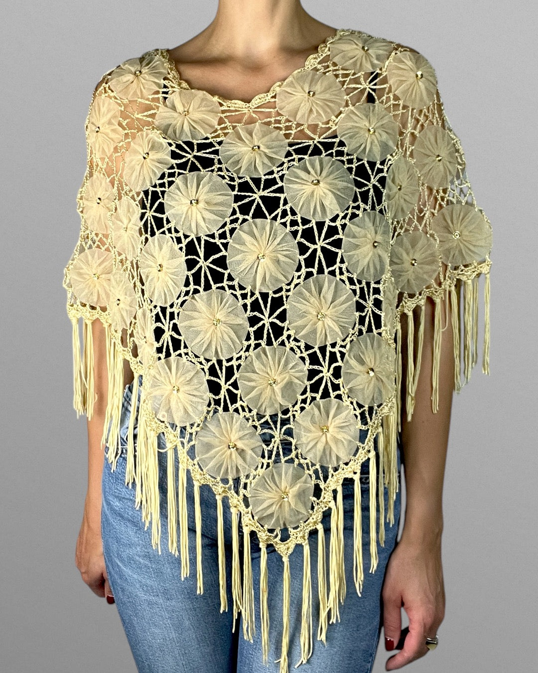 Virkad poncho med blomdetaljer